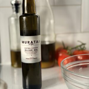 Murataj & Son Extra Virgin Olive Oil 250ml bottle on kitchen counter with tomatoes and glass bowl