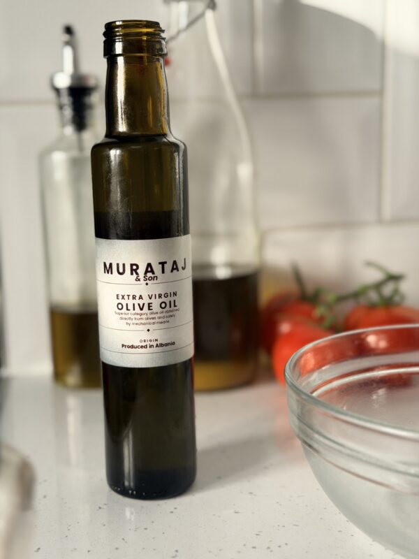 Murataj & Son Extra Virgin Olive Oil 250ml bottle on kitchen counter with tomatoes and glass bowl